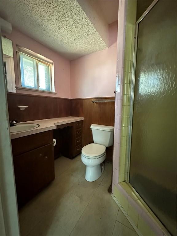 bathroom featuring tile patterned flooring, vanity, a textured ceiling, and walk in shower