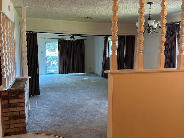 interior space featuring ceiling fan with notable chandelier, light colored carpet, and a textured ceiling