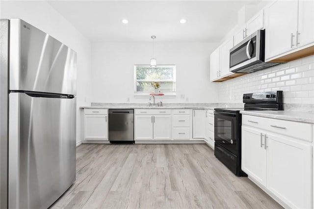 kitchen with sink, white cabinets, light wood-type flooring, and appliances with stainless steel finishes