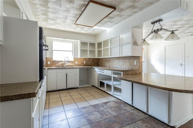 kitchen featuring white cabinets, kitchen peninsula, tasteful backsplash, and sink