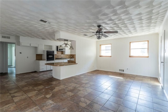 kitchen featuring white cabinetry, ceiling fan, tasteful backsplash, kitchen peninsula, and black oven