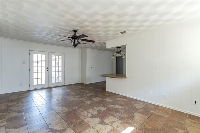 spare room featuring french doors, ceiling fan, and wooden walls