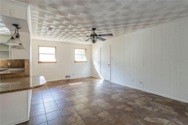 interior space with ceiling fan and wooden walls