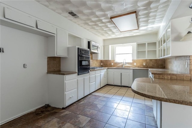 kitchen with dark stone counters, sink, decorative backsplash, white cabinetry, and stainless steel appliances