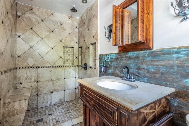 bathroom featuring vanity, a tile shower, and tile walls