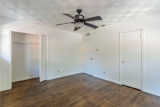 unfurnished bedroom with dark hardwood / wood-style floors, ceiling fan, and multiple closets