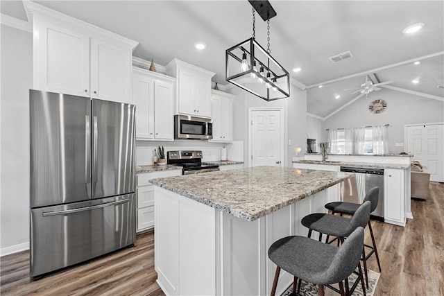 kitchen featuring white cabinets, a center island, ceiling fan, wood-type flooring, and appliances with stainless steel finishes