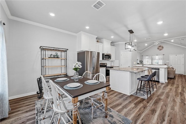 dining room featuring dark hardwood / wood-style flooring, vaulted ceiling, and crown molding