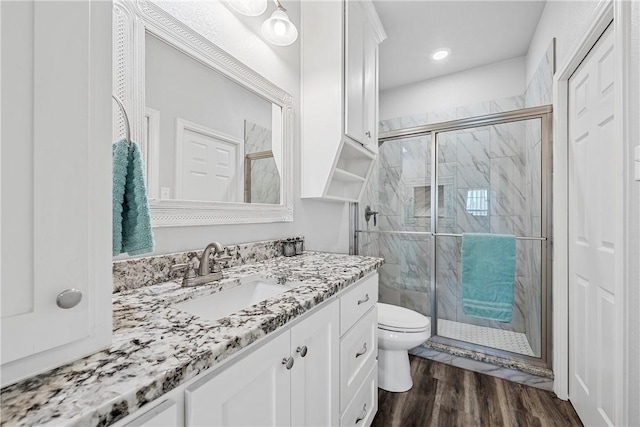 bathroom with toilet, an enclosed shower, vanity, and wood-type flooring