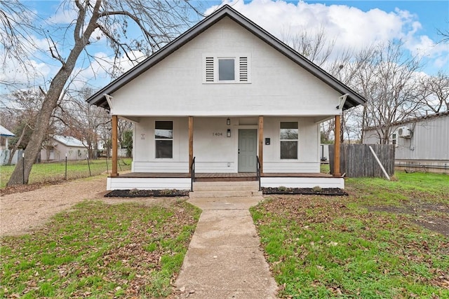 bungalow featuring covered porch and a front yard