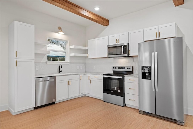 kitchen featuring beam ceiling, white cabinetry, sink, and appliances with stainless steel finishes