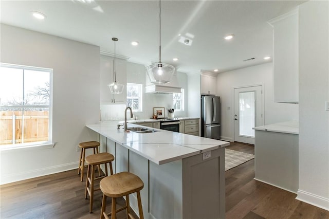 kitchen featuring white cabinetry, stainless steel appliances, dark wood-type flooring, kitchen peninsula, and pendant lighting