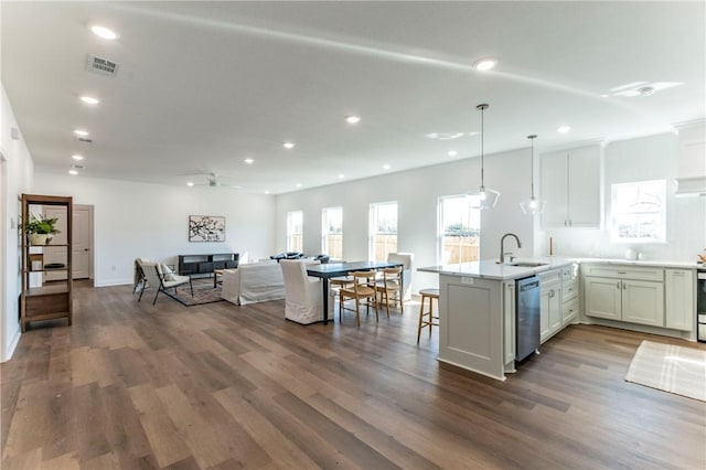 kitchen with dark hardwood / wood-style flooring, white cabinetry, stainless steel dishwasher, and hanging light fixtures