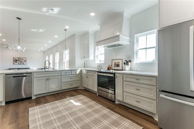 kitchen with stainless steel appliances, hanging light fixtures, premium range hood, and sink