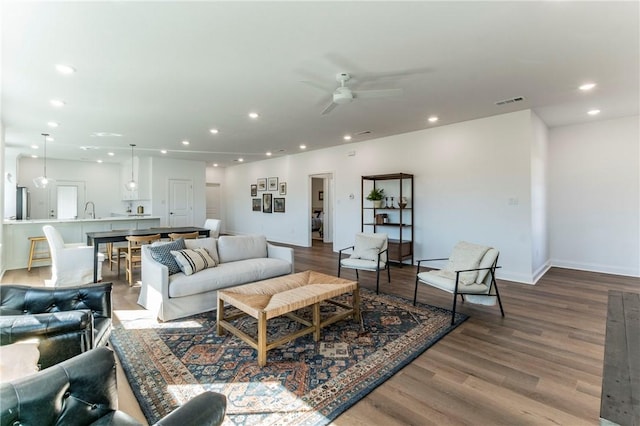 living room featuring wood-type flooring, ceiling fan, and sink