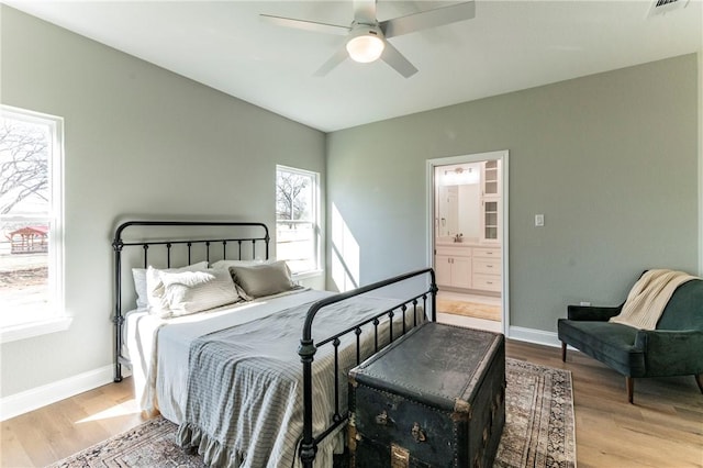 bedroom featuring ceiling fan, light wood-type flooring, and ensuite bath