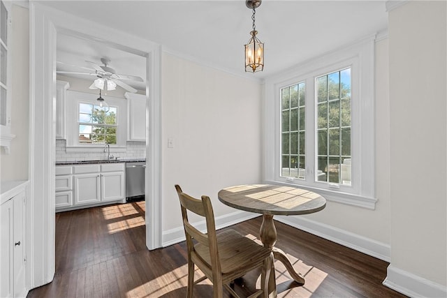 dining room with ceiling fan with notable chandelier, dark hardwood / wood-style flooring, and sink