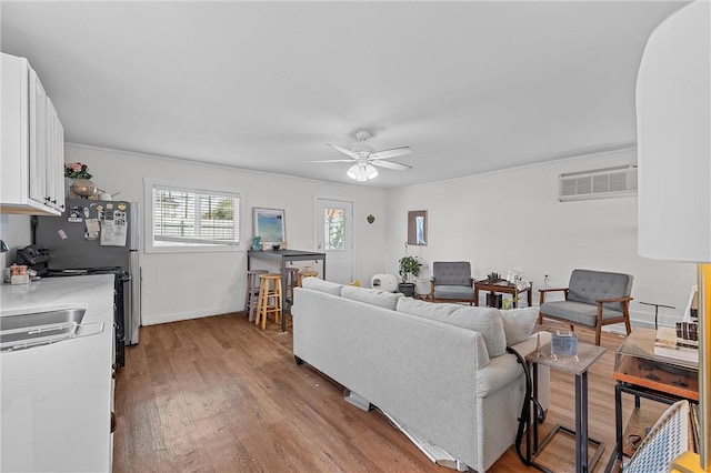 living room featuring light hardwood / wood-style floors, a wall unit AC, and ceiling fan