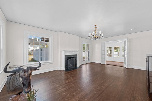 unfurnished living room featuring a healthy amount of sunlight, dark hardwood / wood-style floors, and a notable chandelier