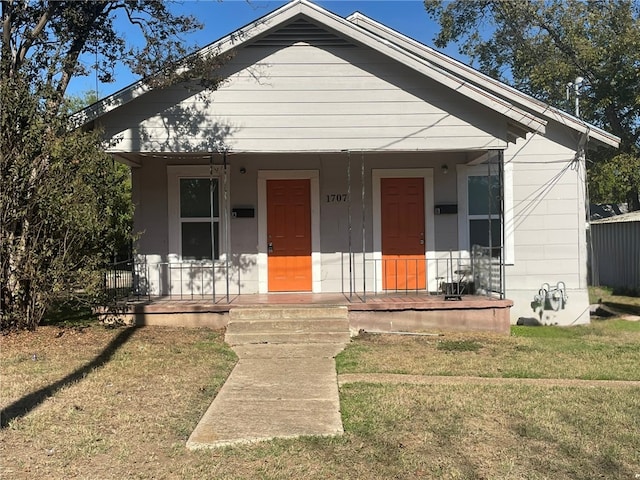 bungalow-style house with a front lawn and covered porch