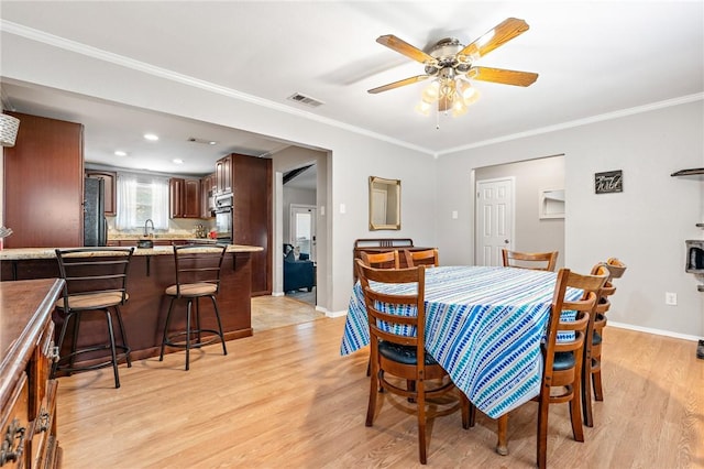 dining area with ceiling fan, light hardwood / wood-style flooring, and ornamental molding