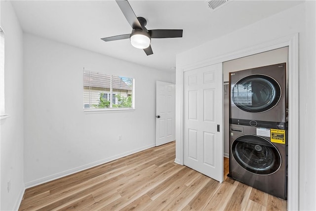 laundry room featuring ceiling fan, light wood-type flooring, and stacked washer and dryer