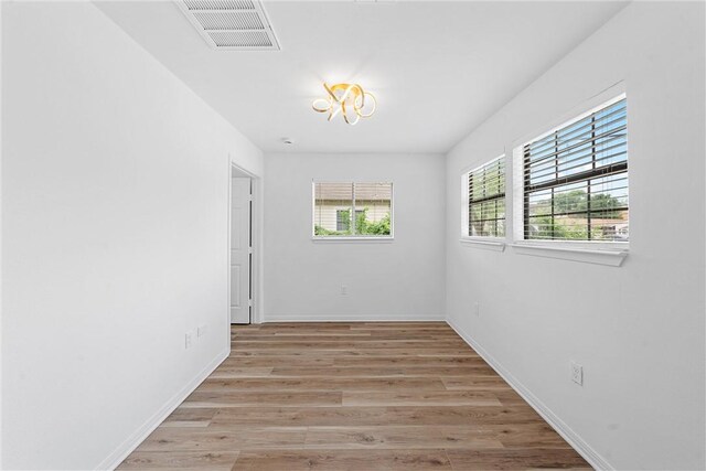 spare room with light hardwood / wood-style floors and an inviting chandelier