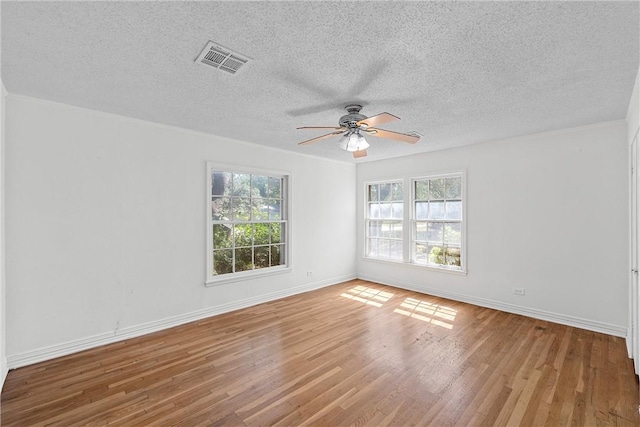 empty room with ceiling fan, hardwood / wood-style floors, a textured ceiling, and ornamental molding