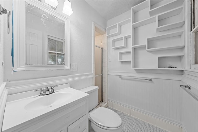 bathroom featuring a textured ceiling, vanity, an enclosed shower, and toilet