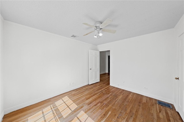 spare room with ceiling fan, ornamental molding, a textured ceiling, and light wood-type flooring