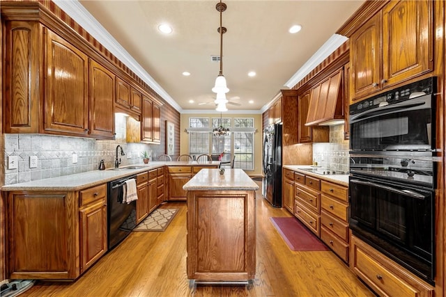 kitchen featuring pendant lighting, black appliances, sink, light hardwood / wood-style flooring, and a kitchen island