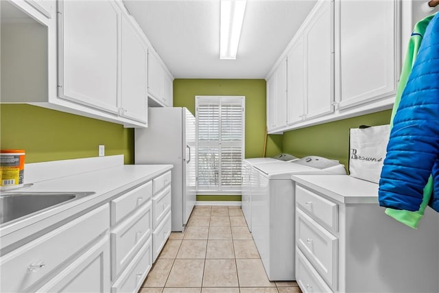 laundry room featuring separate washer and dryer, light tile patterned floors, and cabinets