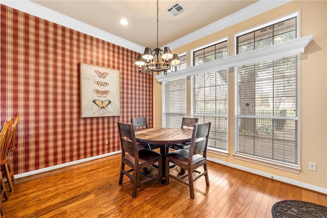 dining area featuring hardwood / wood-style floors, crown molding, and a chandelier