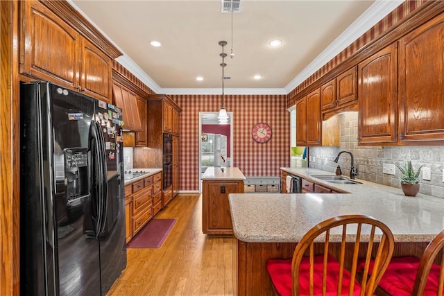 kitchen with kitchen peninsula, crown molding, sink, black appliances, and pendant lighting