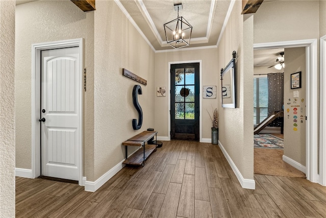 entrance foyer featuring a tray ceiling, a barn door, crown molding, and ceiling fan with notable chandelier