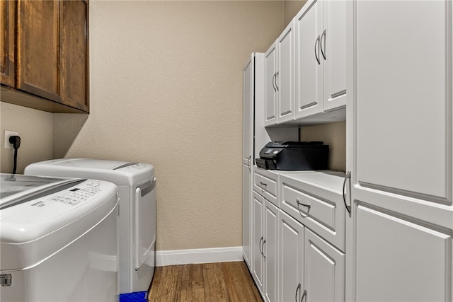 washroom with washing machine and dryer, cabinets, and hardwood / wood-style flooring