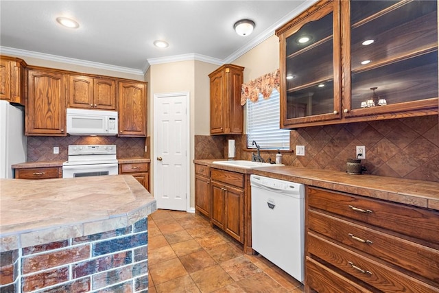 kitchen with light countertops, glass insert cabinets, ornamental molding, a sink, and white appliances