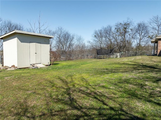 view of yard with an outbuilding, a storage unit, a trampoline, and fence