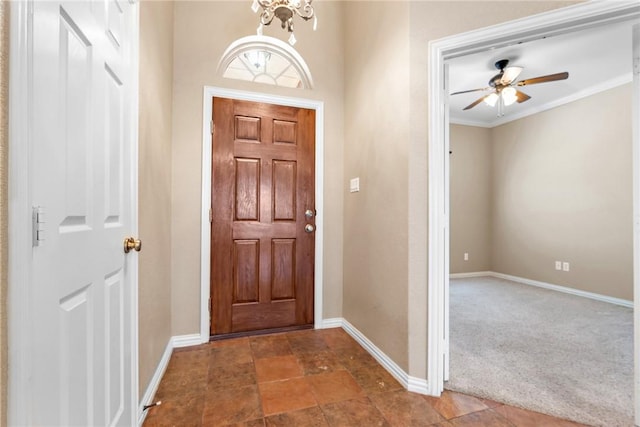 carpeted foyer with crown molding, baseboards, and ceiling fan with notable chandelier