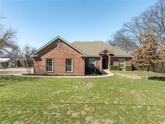 ranch-style home with roof with shingles, a front lawn, and brick siding