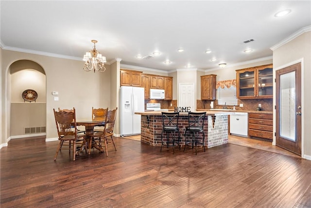 kitchen with visible vents, glass insert cabinets, brown cabinetry, a kitchen island, and white appliances