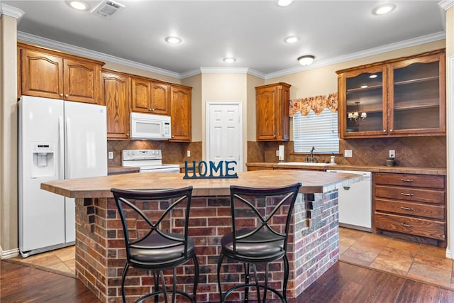 kitchen featuring a center island, brown cabinets, glass insert cabinets, a sink, and white appliances