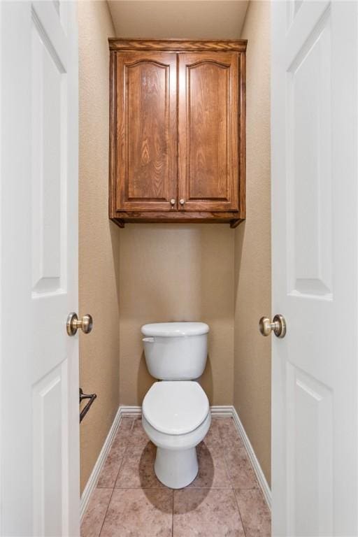 bathroom with toilet, baseboards, and tile patterned floors