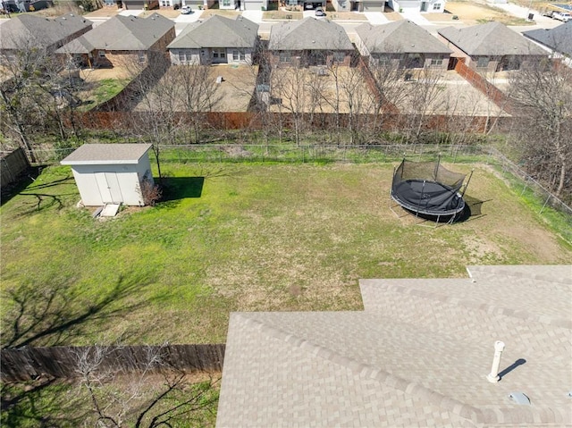 view of yard with a storage shed, a residential view, a trampoline, fence, and an outdoor structure