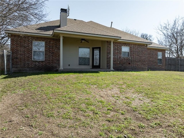 back of property featuring a ceiling fan, a yard, brick siding, and fence