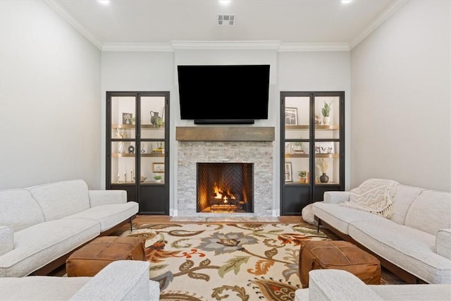 living room featuring ornamental molding, hardwood / wood-style floors, and a stone fireplace