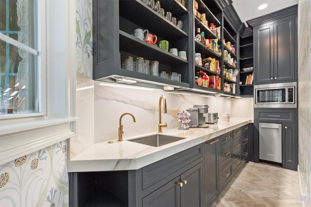 bar featuring light parquet floors, stainless steel microwave, decorative backsplash, light stone countertops, and sink