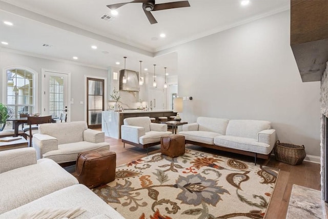 living room with ceiling fan, ornamental molding, and light hardwood / wood-style flooring