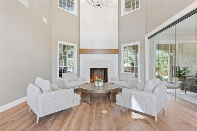 living room with light wood-type flooring, a towering ceiling, and a notable chandelier