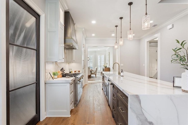 kitchen with white cabinetry, stainless steel appliances, custom range hood, light stone countertops, and pendant lighting